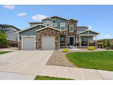 Beautiful two-story home with a stone and blue siding exterior and a well-manicured lawn at 21854 Tyrolite Ave, Parker, CO 80138