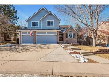 Two-story house with gray siding, two-car garage, and landscaped yard at 6148 W Pacific Cir, Lakewood, CO 80227