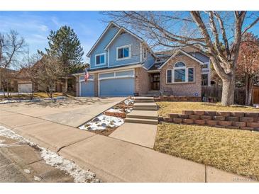 Two-story home with brick and siding exterior, three-car garage, and landscaped yard at 6148 W Pacific Cir, Lakewood, CO 80227