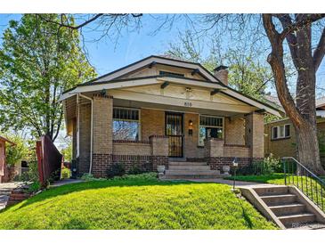 Charming brick home featuring a covered porch, manicured lawn, and easy access via concrete steps at 810 Adams St, Denver, CO 80206
