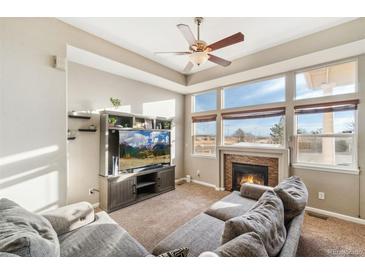 Comfortable living room with a cozy fireplace and large windows at 9752 Dahlia Ln, Thornton, CO 80229