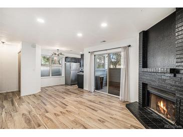 Bright living room features a black brick fireplace, wood floors, and sliding glass doors to a patio at 8035 W Eastman Pl # 106, Lakewood, CO 80227