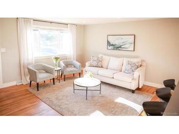 Bright living room with hardwood floors, neutral tones, and a comfortable seating arrangement, creating a welcoming atmosphere at 7100 Saulsbury St, Arvada, CO 80003