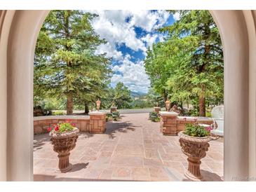 Stunning patio entrance with beautiful planters and stone detail surrounded by lush trees and view at 28 Indian Paintbrush Dr, Golden, CO 80401