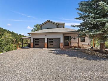 Beautiful exterior features a gray home with two-car garage, front porch and lots of parking space at 31518 Niakwa Rd, Evergreen, CO 80439