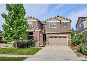 Two-story home with a two-car garage, stone accents, manicured lawn, and basketball hoop at 10397 Helsinki St, Parker, CO 80134