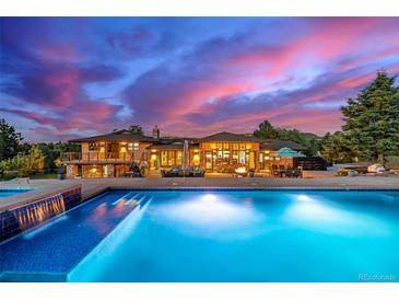 Stunning pool with integrated waterfall feature, deck area, and beautiful views of the estate at sunset at 5727 Colorow Dr, Morrison, CO 80465