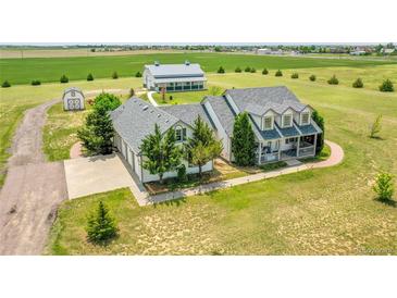 Expansive property featuring a two-story home, barn, outbuilding, and mature trees at 56920 E 42Nd Ct, Strasburg, CO 80136