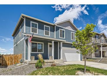 Inviting home featuring a covered porch, two-car garage, and manicured front yard at 2417 Mountain Sky Dr, Fort Lupton, CO 80621