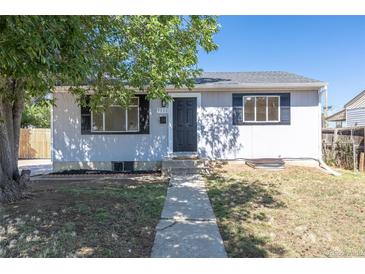 Charming single-story home with gray siding, black door, and tidy front yard landscaping under a clear blue sky at 7111 Clermont St, Commerce City, CO 80022