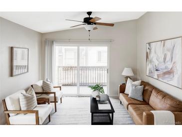 Bright living room featuring a ceiling fan, a sliding glass door to the balcony, and comfortable seating at 8761 W Berry Ave # 202, Littleton, CO 80123