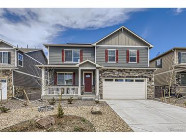 Charming two-story home with stone accents, red shutters, landscaped yard, and a welcoming front porch at 27425 E Byers Pl, Aurora, CO 80018