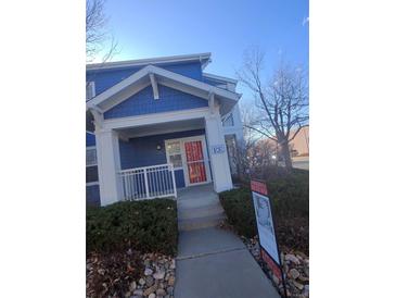 Inviting blue home with a covered front porch, white pillars, and a bright red door at 2793 Roslyn St, Denver, CO 80238