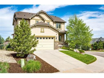 Stunning two-story home featuring a two-car garage and manicured front yard with mature trees under a bright blue sky at 2115 Holmby Ct, Castle Rock, CO 80104