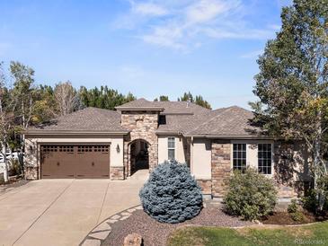 Stunning home featuring a stone archway, mature trees, and a well-maintained yard at 6449 E 163Rd Ave, Brighton, CO 80602