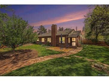 Beautiful brick home featuring a spacious backyard with a brick patio and lush green lawn under a colorful sunset at 1900 Magnolia St, Denver, CO 80220