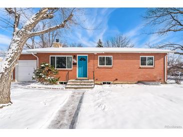 Charming brick home with a bright blue front door and a snow-covered yard at 6371 Iris Ct, Arvada, CO 80004