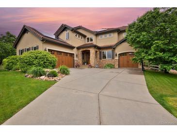 Inviting two-story home featuring a stone-accented facade, solar panels, a well-manicured lawn, and a large driveway at 14370 Osage St, Westminster, CO 80023