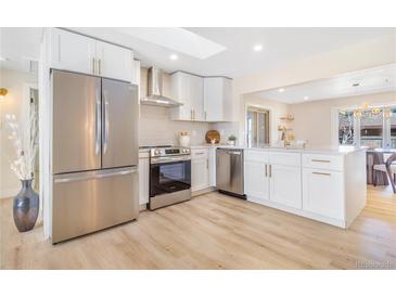 Bright kitchen with stainless steel appliances, white cabinetry, and modern countertops at 1240 S Chase Ct, Lakewood, CO 80232