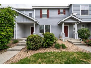 Charming townhome featuring a covered porch, landscaped front yard, and red door at 19249 E 58Th Ave # D, Denver, CO 80249