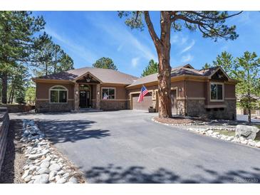 A single Gathering house with stone and stucco accents, long paved driveway, and manicured landscaping at 670 Independence Dr, Larkspur, CO 80118