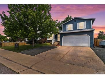 Charming two-story home featuring a two-car garage, lush front yard, and beautiful twilight sky at 8977 W Toller Ave, Littleton, CO 80128