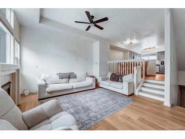 Bright living room featuring white sofas, a modern ceiling fan, and an open floor plan at 12063 Monaco Ct, Brighton, CO 80602