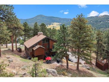 Stunning mountain home with a spacious deck, red umbrella, and lush green trees at 7282 Silverhorn Dr, Evergreen, CO 80439