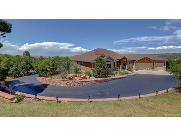 Beautiful single-Gathering home featuring a circular driveway, lush landscaping, and a stone-accented facade, evoking curb appeal at 2941 Castle Butte Drive Dr, Castle Rock, CO 80109