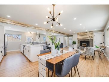 Bright, open-concept living room featuring wood floors, modern lighting, fireplace, and seamless flow to the dining area at 5895 S Huron St, Littleton, CO 80120