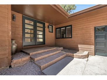 Charming home entrance with double doors and brick steps at 8782 S Ault Ln, Morrison, CO 80465