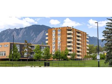 Brick apartment building featuring multiple balconies with mountain views and a green lawn at 850 20Th St # 201, Boulder, CO 80302