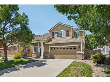 Charming two-story home featuring manicured lawn, mature trees, and a spacious two car garage at 7371 S Mobile St, Aurora, CO 80016