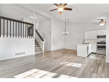 Spacious living room with hardwood floors, lots of natural light, stairs to 2nd floor, and kitchen at 10731 W 63Rd Ave # A, Arvada, CO 80004