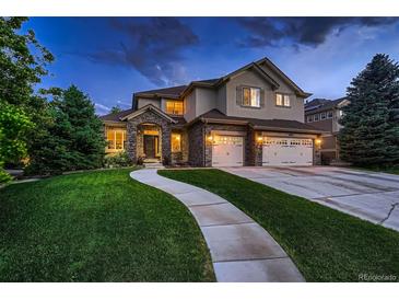 Two-story house with stone accents, landscaped yard, and a three-car garage at 5458 W Calhoun Ave, Littleton, CO 80123