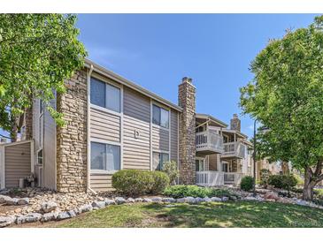 Beautiful condo exterior featuring stone accents, wood siding, a well-manicured lawn, and mature trees at 4400 S Quebec St # D203, Denver, CO 80237