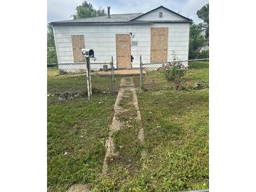 View of a boarded-up home with a weathered walkway, a mailbox, and a chain-link fence at 3701 W 9Th Ave, Denver, CO 80204