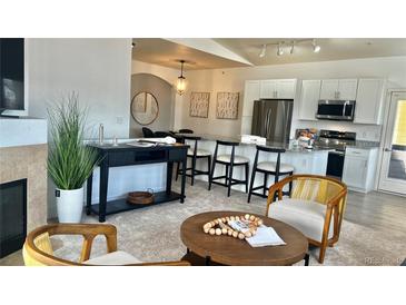 Bright living room with a modern fireplace and stylish decor open to kitchen with granite countertops and breakfast bar seating at 9471 Ashbury Cir # 202, Parker, CO 80134