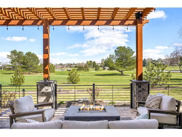 Inviting patio with a fire pit, comfortable seating, and a pergola overlooking a lush green golf course at 3930 S Pinehurst Cir, Denver, CO 80235