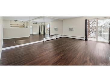 Bright living room with dark laminate floors, a balcony, and mirrored wall at 310 S Ames St # 11, Lakewood, CO 80226