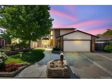 Charming two-story home with a lush front yard, brick accents, and a two-car garage on a twilight at 3870 S Ouray Way, Aurora, CO 80013