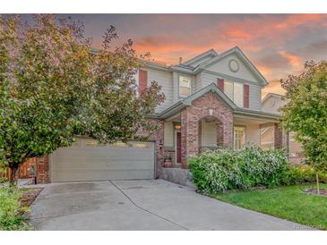 Charming two-story home featuring a brick archway, lush landscaping, and attached two-car garage at 129 N Irvington St, Aurora, CO 80018