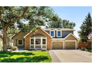 Inviting two-story home with a brick facade, attached two-car garage, mature trees and a well-manicured lawn at 16750 E Prentice Ave, Centennial, CO 80015