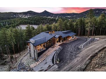 Stunning exterior with a modern design, beautiful stone accents, and mountain views at sunset at 21429 Trappers Trl, Morrison, CO 80465