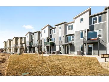 Modern townhomes feature gray siding, balconies, and contemporary architectural details on a sunny day at 2672 W 68Th Ave, Denver, CO 80221