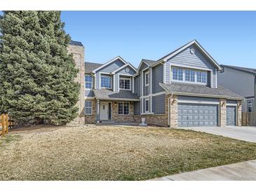 Charming two-story home with blue siding, brick accents, an attached two car garage, and a well-manicured front yard at 6493 W 98Th Ct, Westminster, CO 80021