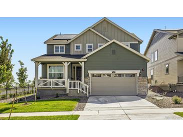 Two-story home with a covered porch, two-car garage, and well-maintained lawn and garden at 627 Nightsky St, Erie, CO 80516
