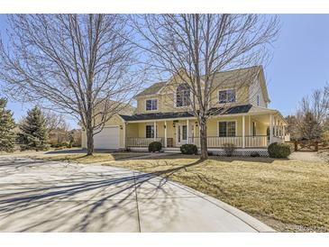 Inviting yellow two-story home boasting a charming wrap-around porch and a well-manicured lawn at 7440 W 94Th Pl, Westminster, CO 80021