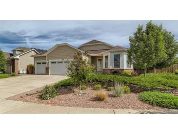 Charming tan single-Gathering home with a well-manicured front yard and a two-car garage at 4495 Windmill Dr, Brighton, CO 80601