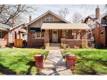 Charming brick home with a inviting covered front porch and well-manicured lawn at 910 Steele St, Denver, CO 80206
